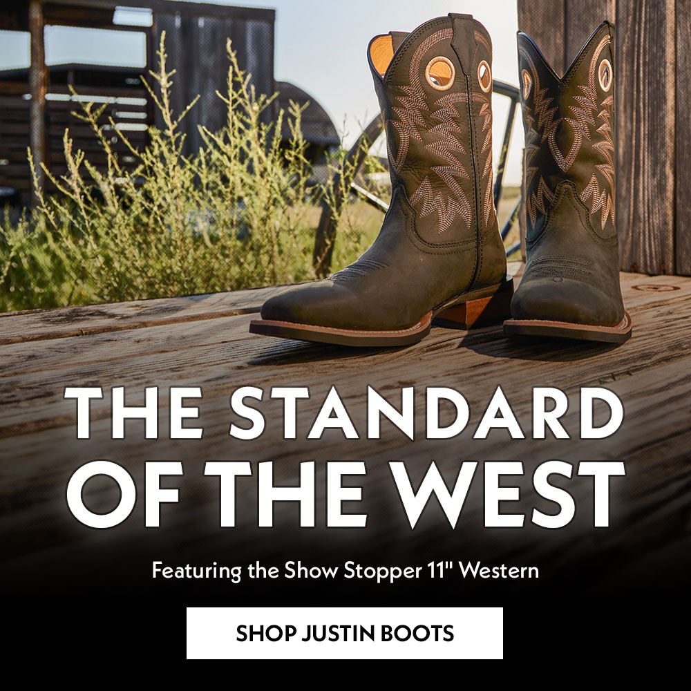 The Standard of the West. Featuring the Show Stopper 11" Western. Shop Justin Boots. The Show Stopper 11" Western boot in black sitting on wood.